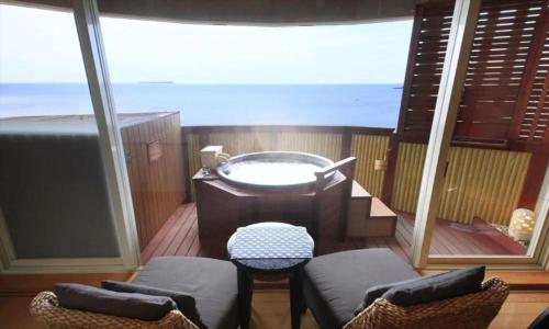 a balcony with a tub and chairs on a boat at Luxury Wa Hotel Kaze No Kaori in Ito