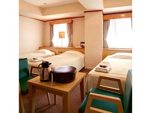 a room with two beds and a table and chairs at Okinawa Sunplaza Hotel in Naha