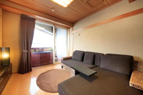 a living room with a couch and a large window at Luxury Wa Hotel Kaze No Kaori in Ito