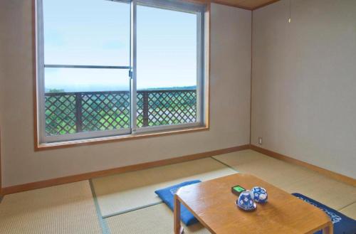 a living room with a table and a large window at Kuju Kogenso Hotel in Kokonoe