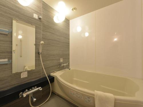 a bathroom with a bath tub and a mirror at Oze Iwakura Resort Hotel in Tokura