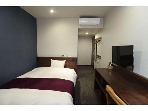 a hotel room with a bed and a flat screen tv at AKISAWA HOTEL in Shimanto