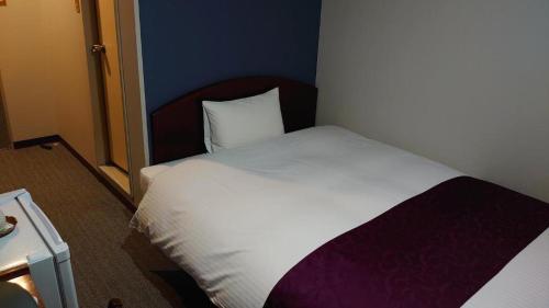 a small bedroom with a white bed and a pillow at AKISAWA HOTEL in Shimanto
