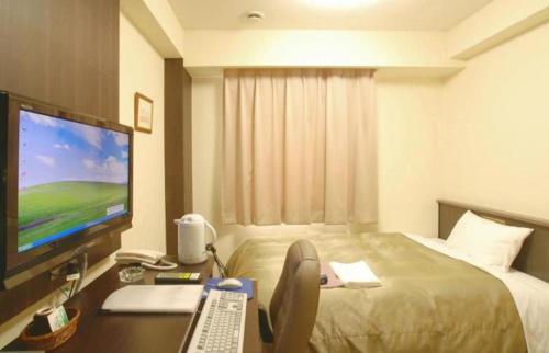a hotel room with a bed and a desk with a computer at Chino Station Hotel in Chino