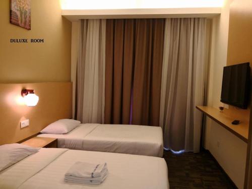 a hotel room with two beds and a flat screen tv at Lipis Plaza Hotel in Kuala Lipis