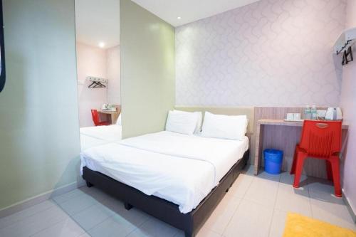 a small bedroom with a bed and a red chair at Cappuccino Hotel @ Mount Austin in Johor Bahru