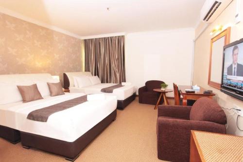 a hotel room with two beds and a flat screen tv at Pelican Hotel in Batu Pahat