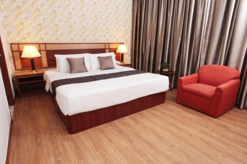 a bedroom with a bed and a red chair at Pelican Hotel in Batu Pahat