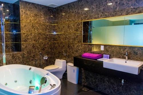 a bathroom with a tub and a sink and a toilet at MH Hotels Ipoh in Kampong Simee