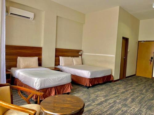 a hotel room with two beds and a table at The Regency Hotel Seri Warisan in Taiping