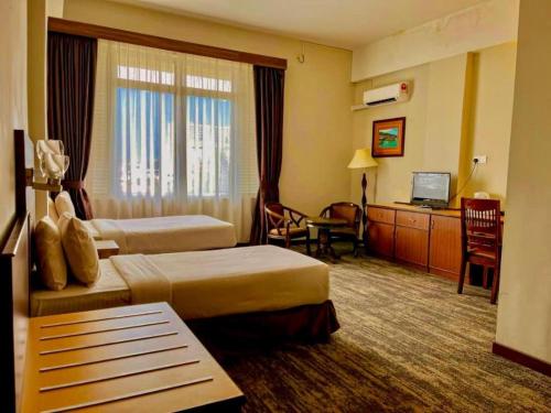 a hotel room with two beds and a television at The Regency Hotel Seri Warisan in Taiping