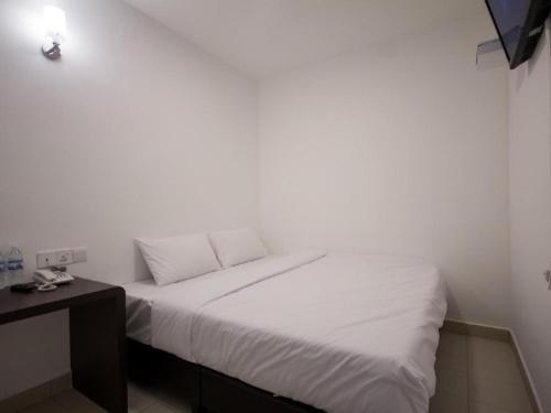 a white bed in a room with a table at D Nice Hotel in George Town
