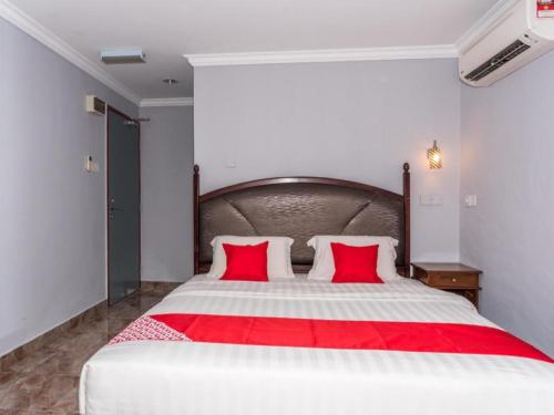 a bedroom with a large bed with two red pillows at OYO 890 Hotel RK Cahaya in Labuan