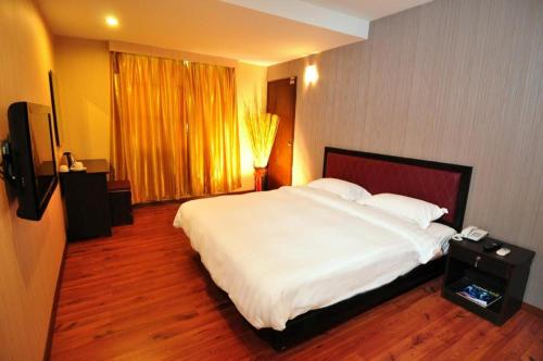 a bedroom with a large white bed and a television at Bay Hotel in Lahad Datu