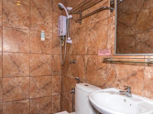 a bathroom with a toilet and a sink and a mirror at OYO 890 Hotel RK Cahaya in Labuan