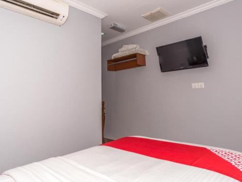 a bedroom with a bed and a tv on the wall at OYO 890 Hotel RK Cahaya in Labuan