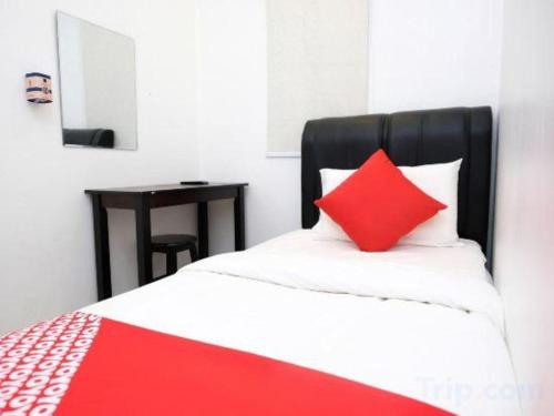 a red pillow sitting on top of a bed at OYO 718 Mr J Hotel Wakaf Che Yeh 1 in Kota Bharu