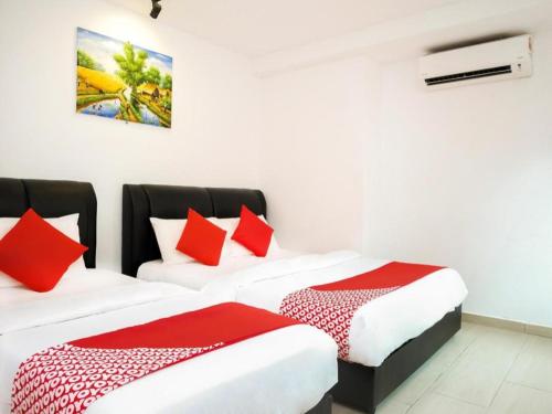 two beds in a room with red and white pillows at OYO 718 Mr J Hotel Wakaf Che Yeh 1 in Kota Bharu