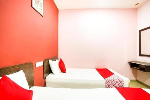 a small room with two beds with red walls at OYO 89539 Hotel Siswa in Kampar