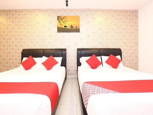 two beds in a room with red pillows at OYO 718 Mr J Hotel Wakaf Che Yeh 1 in Kota Bharu