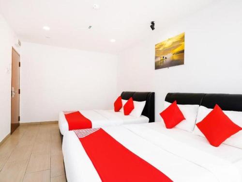 a bedroom with two white beds with red pillows at OYO 718 Mr J Hotel Wakaf Che Yeh 1 in Kota Bharu