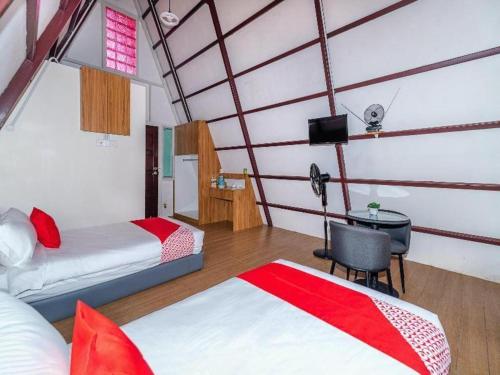 a room with two beds and a desk with a television at Dreamland Beach Holiday in Kudat