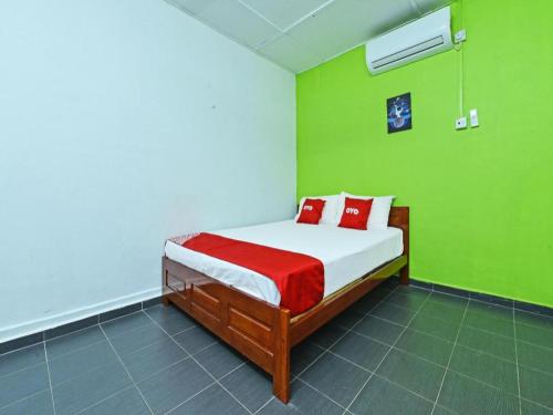 a bedroom with a bed with red pillows and green walls at OYO 90315 Chalet Pantai Rantau Panjang in Kuala Rompin