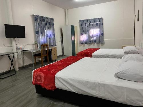 a bedroom with two beds and a desk with a computer at OYO 90462 Padang Besar Green Inn in Padang Besar