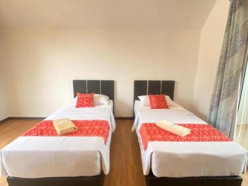 two beds in a room with red pillows on them at OYO HOME 90688 Kundasang Mount Garden in Ranau