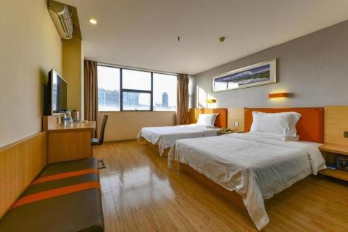 a hotel room with two beds and a flat screen tv at 7 Days Premium Zhuhai Gongbei Light Railway Branch in Zhuhai