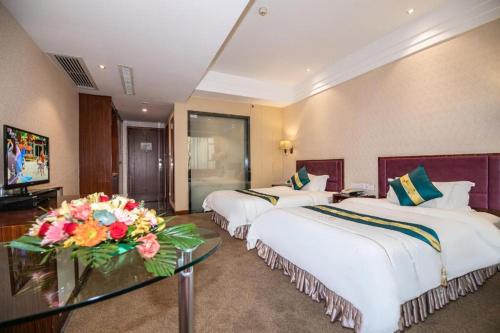 a hotel room with three beds and a table with flowers at Shunde Emperor Hotel in Shunde