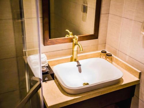 a bathroom sink with a gold faucet on it at James Joyce Coffetel Xian Big Goose Pagoda Tang Paradise Branch in Xi'an