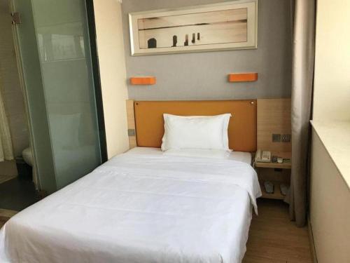 a bedroom with a white bed in a room at 7 Days Premium Zhuhai Gongbei Light Railway Branch in Zhuhai
