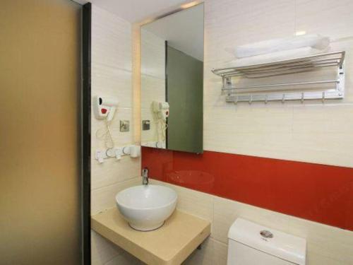 a bathroom with a white sink and a mirror at 7 Days Premium Zhuhai Gongbei Light Railway Branch in Zhuhai