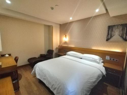a hotel room with a white bed and a desk at James Joyce Coffetel Xian Big Goose Pagoda Tang Paradise Branch in Xi'an