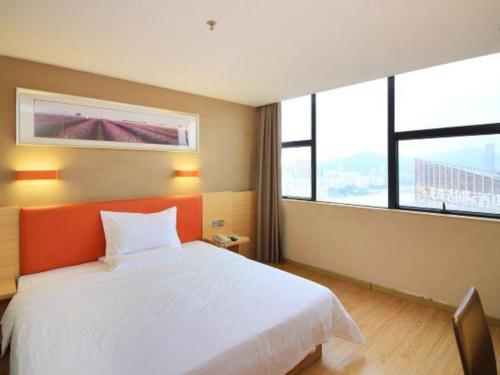 a bedroom with an orange and white bed and windows at 7 Days Premium Zhuhai Gongbei Light Railway Branch in Zhuhai