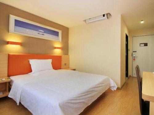 a bedroom with a large white bed and a table at 7 Days Premium Zhuhai Gongbei Light Railway Branch in Zhuhai