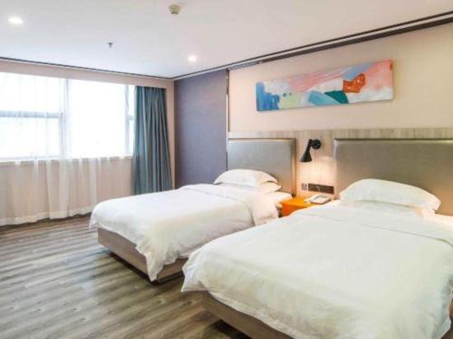 a hotel room with two beds and a window at 7 Days Premium Zhuhai Gongbei Light Railway Branch in Zhuhai