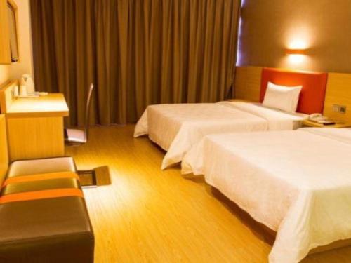 a hotel room with two beds and a chair at 7 Days Premium Zhuhai Gongbei Light Railway Branch in Zhuhai