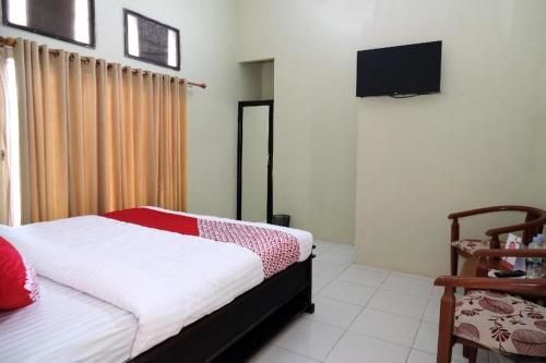 a bedroom with a bed and a television in it at Hotel O Abz Guest House Syariah in Jambi