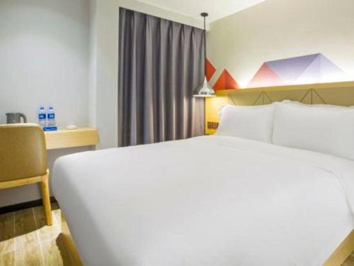 a bedroom with a large white bed and a desk at Borrman Hotel Zhuhai Gongbei Port Fuhuali Light Rail in Zhuhai