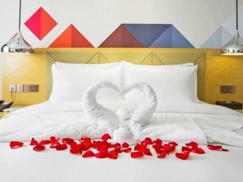 two swans making a heart on a bed with red roses at Borrman Hotel Zhuhai Gongbei Port Fuhuali Light Rail in Zhuhai