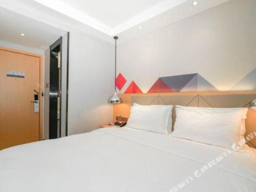 a bedroom with a large white bed with white pillows at Borrman Hotel Zhuhai Gongbei Port Fuhuali Light Rail in Zhuhai