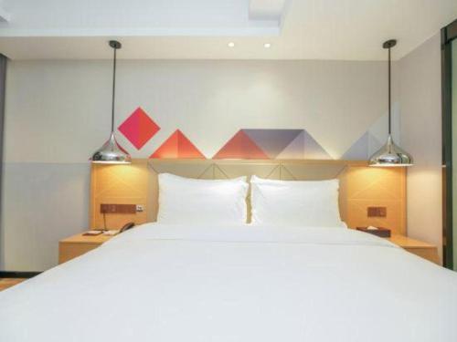 a bedroom with a large bed with two lights at Borrman Hotel Zhuhai Gongbei Port Fuhuali Light Rail in Zhuhai