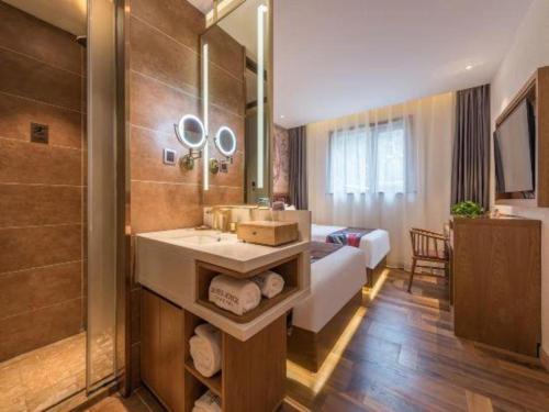 a bathroom with a sink and a shower and a bed at James Joyce Coffetel Beijing Station in Beijing