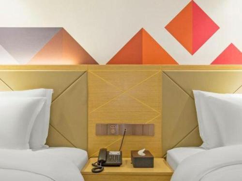 a hotel room with two beds and a phone at Borrman Hotel Zhuhai Gongbei Port Fuhuali Light Rail in Zhuhai