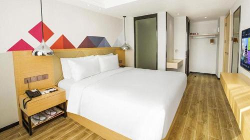 a hotel room with a large white bed in a room at Borrman Hotel Zhuhai Gongbei Port Fuhuali Light Rail in Zhuhai