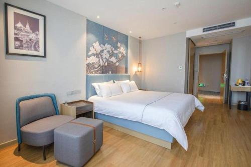 a bedroom with a large white bed and a chair at Magnotel Hotel Dongxing Guomen Port in Fangcheng
