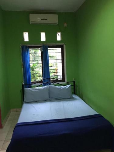 a bed in a green room with a window at Hotel O Wisma Pinggir in Tanjung Pinang 