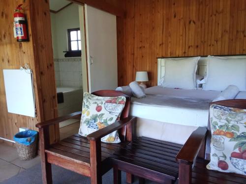 a bedroom with a bed and a chair and a mirror at The Retreat Country Lodge in Romelcoh